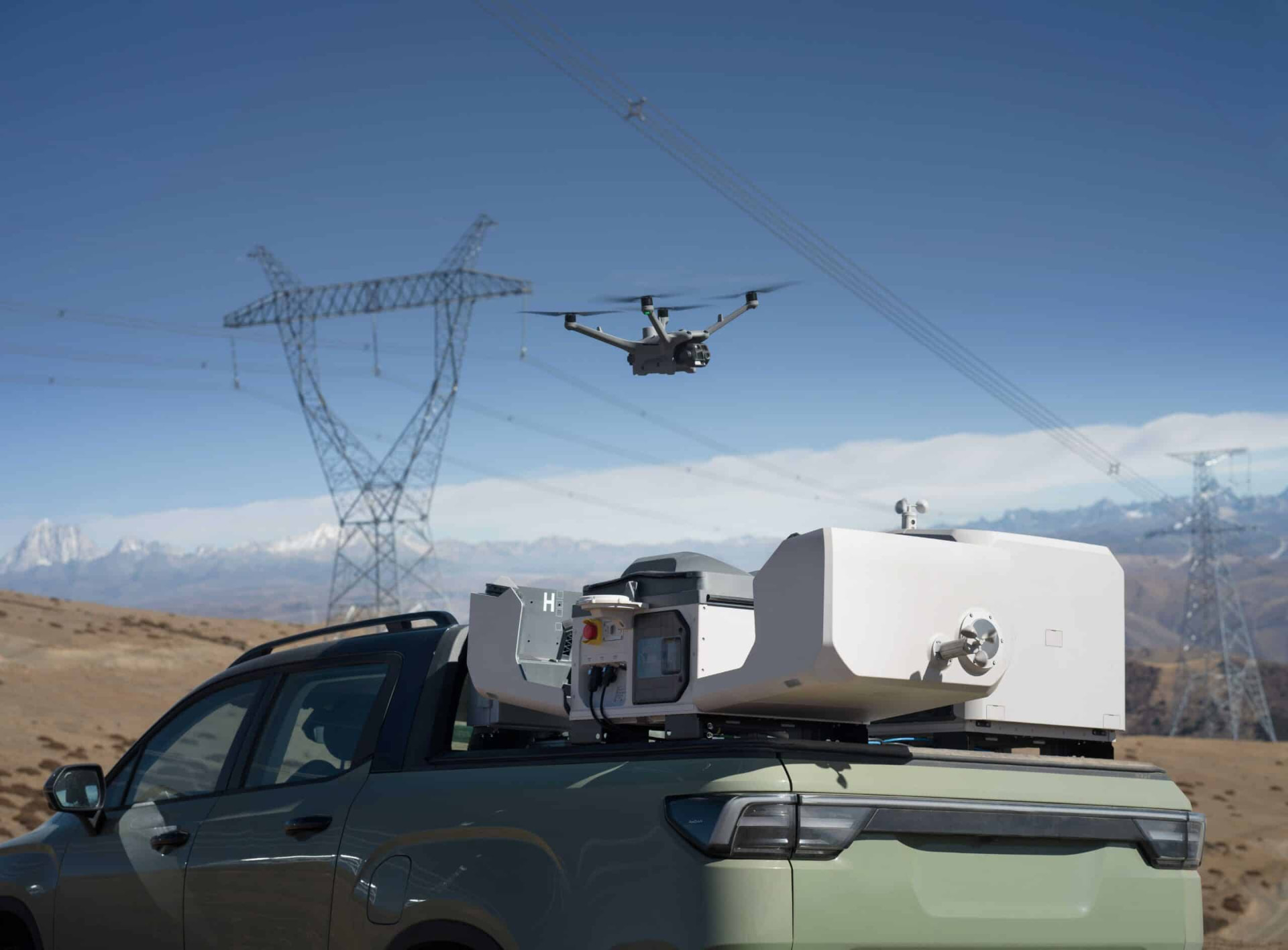 Mobile drone station on a pickup with an inspection drone launching above it in the mountains.