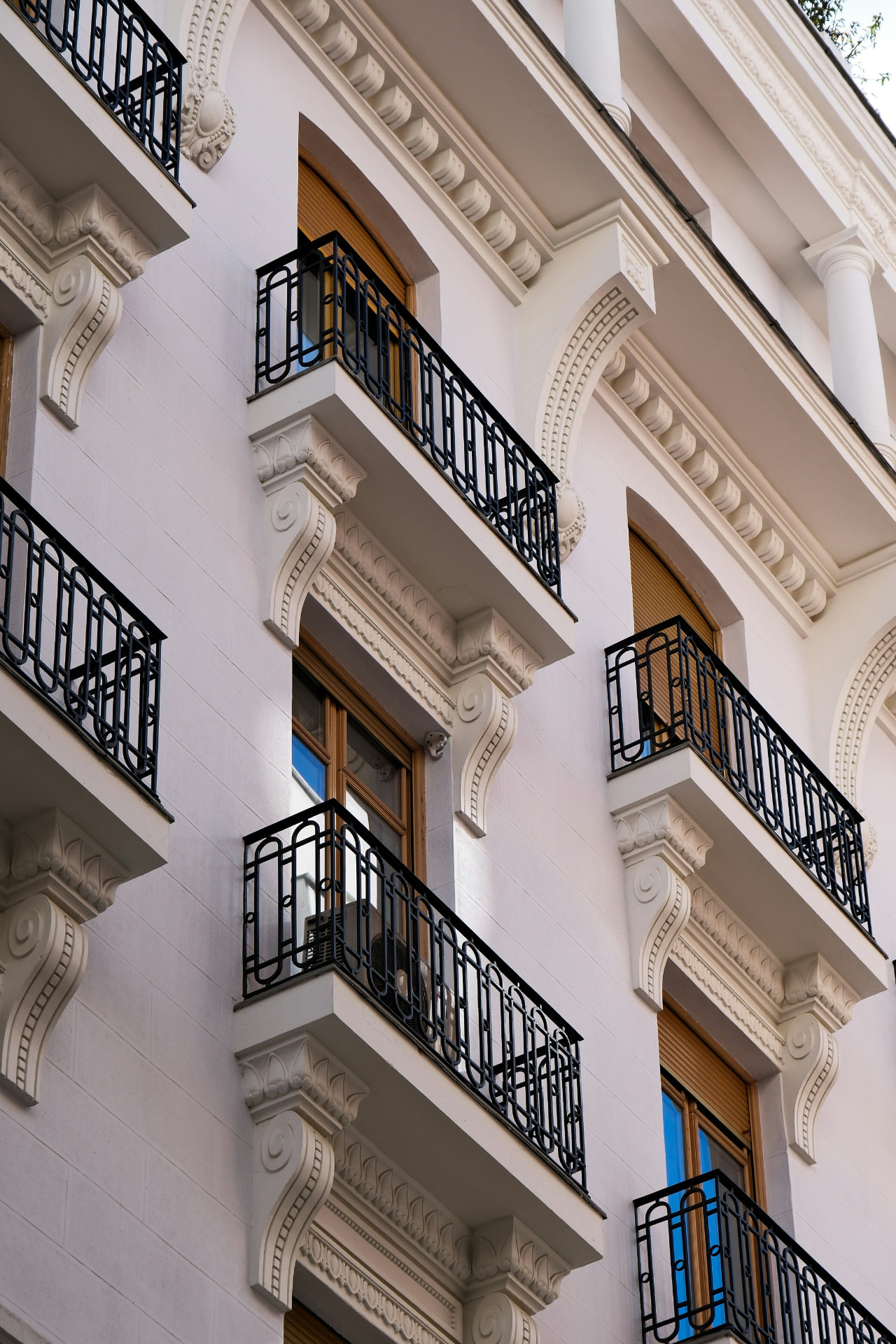 Classical stucco façade with wrought-iron balconies seen close up. (AI-generated image)